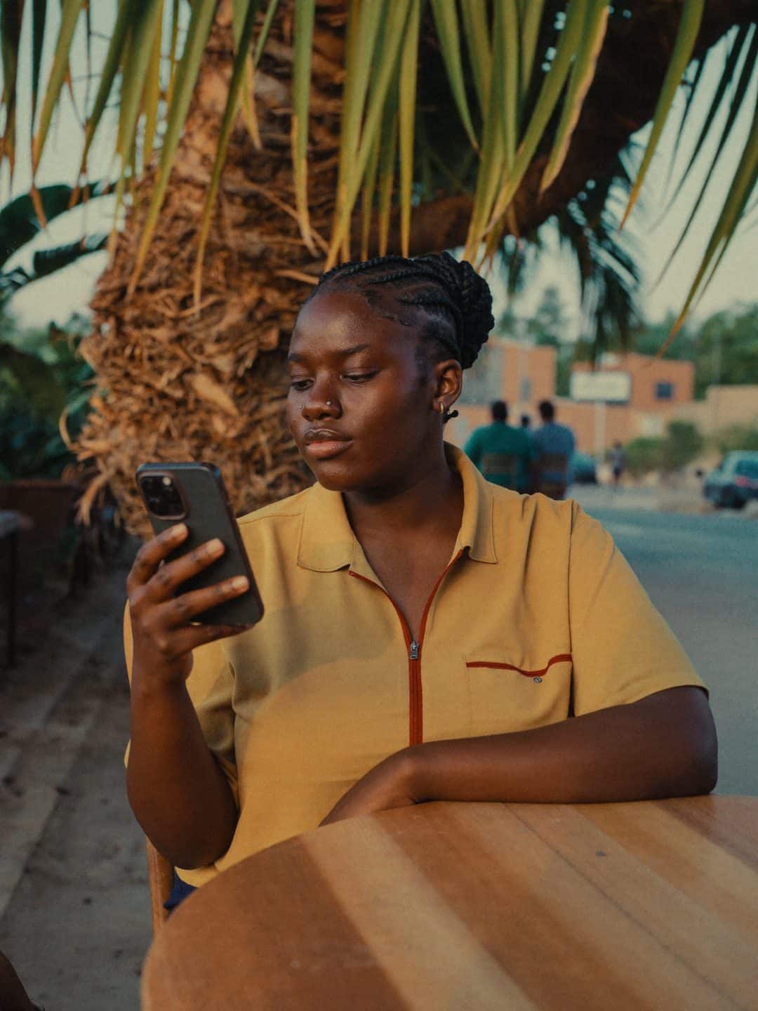 A young woman looks at her phone on a cafe terrace at dusk