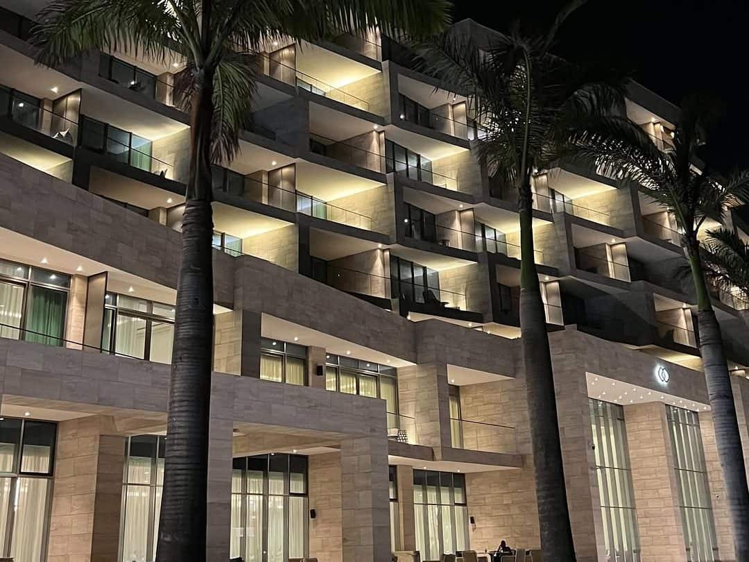 Hotel facade lit at night, balconies and palm trees