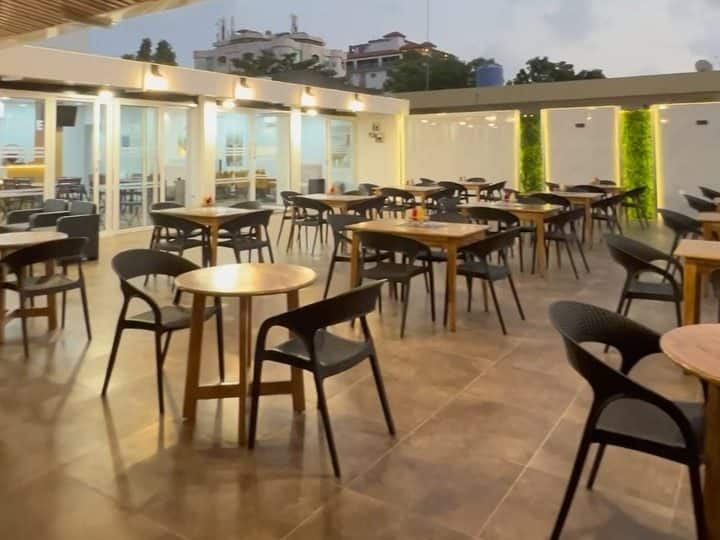 Restaurant terrace at dusk, wooden tables under a slatted pergola
